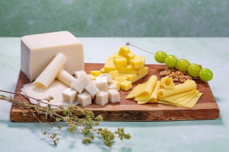 An image of various cheeses on a wooden board